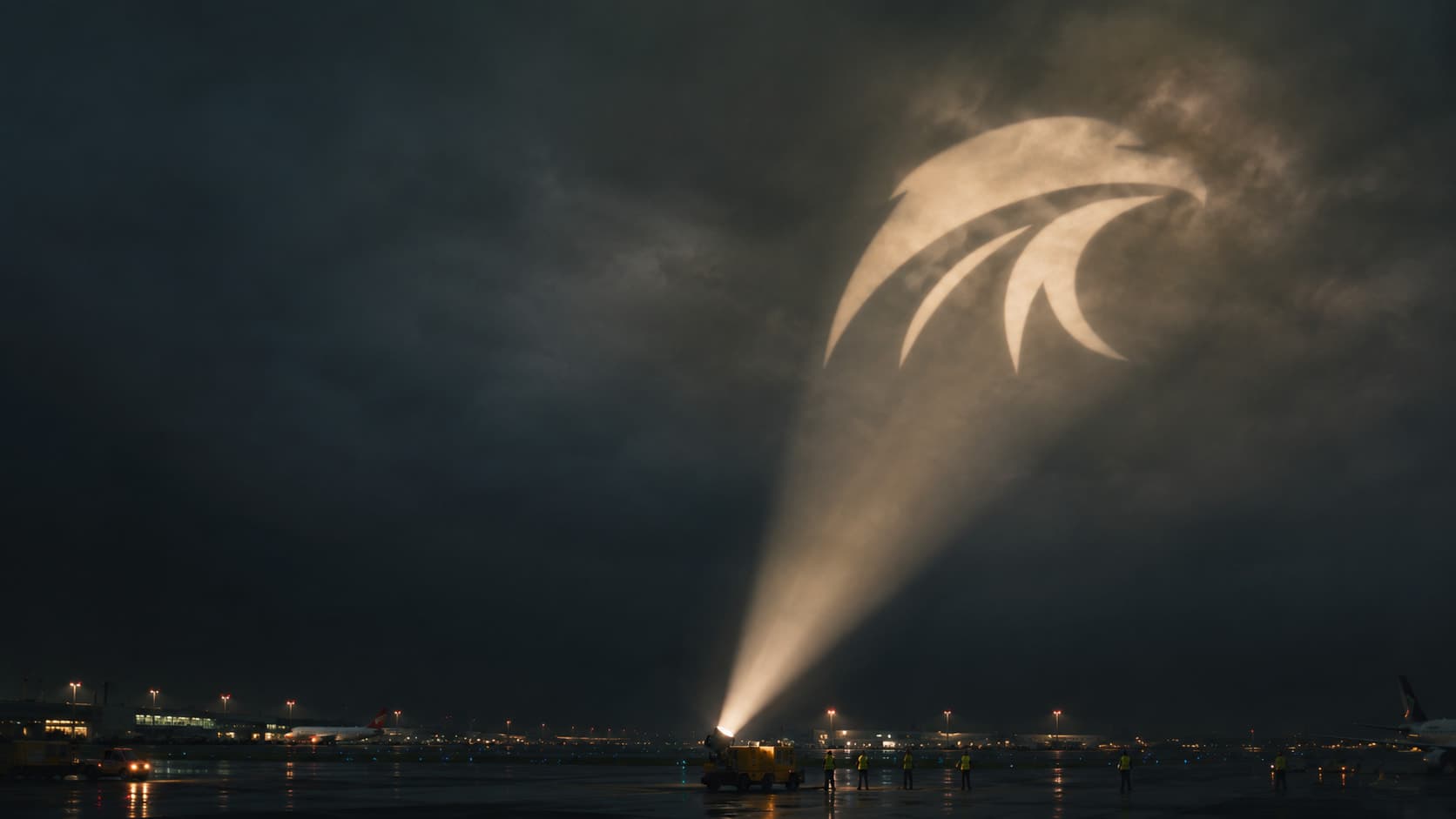 A searchlight projecting the Arnett UK eagle mark into the night sky above an airfield
