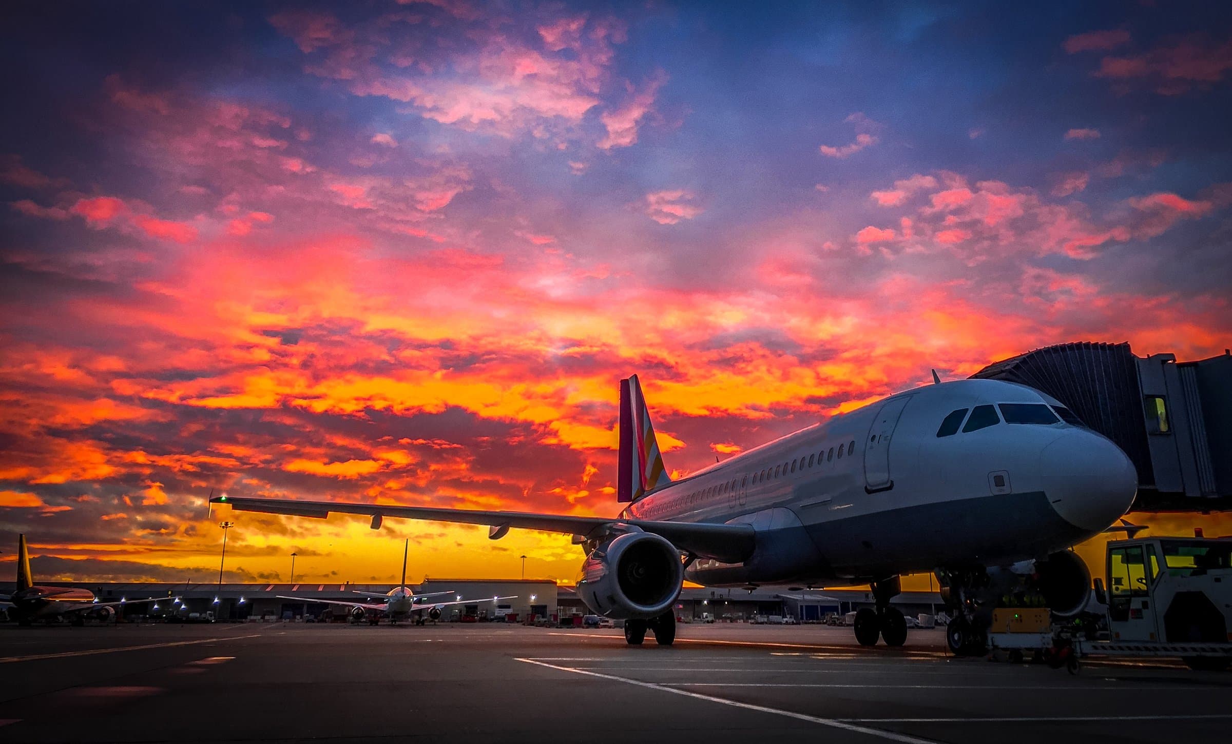 Aircraft at the gate under a red evening sky