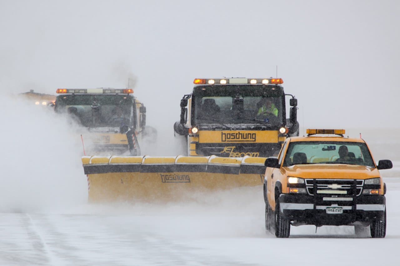 Snow sweepers clearing a runway in winter conditions
